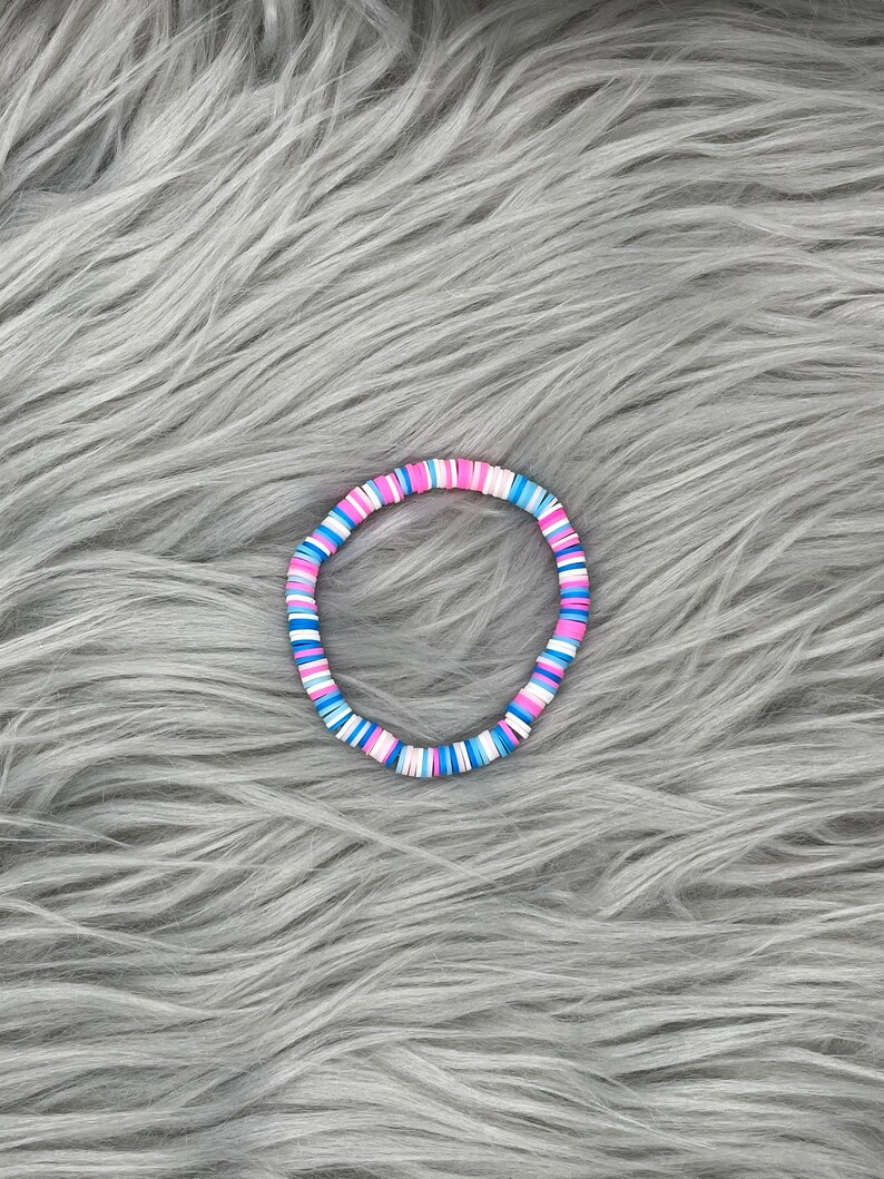 May include: A colorful bracelet made of small, round beads in shades of pink, blue, and white.