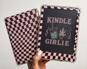 May include: A Kindle e-reader with a pink and black checkered case. The screen displays the text "KINDLE GIRLIE" with a graphic of a drink and flames. The case is clear with a pink and black checkered pattern.