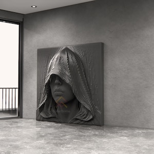 May include: A square wall art piece featuring a three-dimensional, dark grey relief sculpture of a human face partially obscured by a hooded cloak. The surface is composed of vertical, parallel lines that create a textured, layered effect.