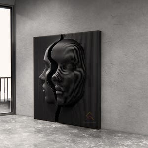 Può includere: Un'opera d'arte da parete nera che raffigura due volti divisi al centro. I volti sono realizzati con listelli verticali paralleli che creano una texture tridimensionale a coste. Il design è simmetrico, con un volto di profilo e uno frontale.