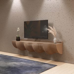 May include: A contemporary wooden floating TV unit with a distinctive, curved design. The unit is light brown and has a series of wave-like shapes. A black TV is mounted above the unit. Decorative vases with plants are placed on the unit.