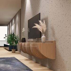 May include: A contemporary living room featuring a wall-mounted television above a wooden console with a distinctive, curved design. A vase with dried plants and a small white vase are on the console. A potted plant and a blue rug are also visible.