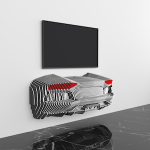 May include: A modern, wall-mounted entertainment center with a unique design, featuring a black and white striped pattern and red accent lights. A black flat-screen TV is mounted above it. The room has a minimalist design.