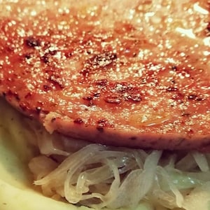 Könnte beinhalten: Nahaufnahme einer gebratenen Wurst, die auf einem Bett aus geriebenem Weißkohl serviert wird.