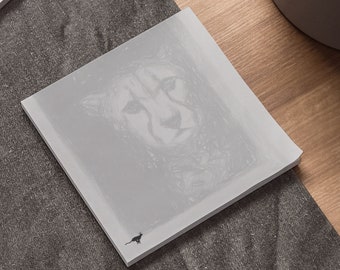 May include: A gray notepad with a black and white illustration of a cheetah's face. A small black silhouette of a cat is in the bottom left corner.