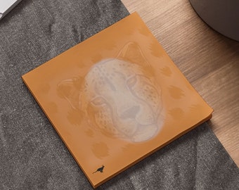 May include: A brown sticky note with a white cheetah face printed on it. The cheetah face is partially transparent, revealing the brown background of the sticky note.