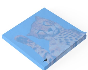 May include: A square, light blue sticky note pad featuring a cheetah illustration. The cheetah is depicted with closed eyes and its paw raised. A small black silhouette of a cat is in the lower right corner.