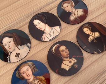 May include: Six round coasters featuring portraits of historical figures. Each coaster displays a different portrait, showcasing women in period clothing and jewelry. The coasters are set against a light wood grain background.
