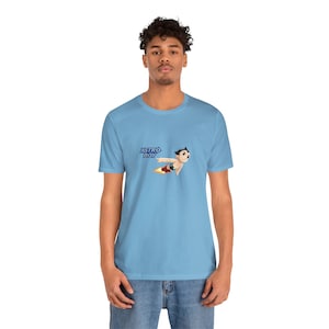 May include: A light blue t-shirt with a graphic of Astro Boy flying with a rocket. The text "ASTRO BOY" is printed in blue on the shirt.