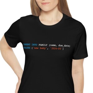 May include: A black t-shirt with the text "INSERT INTO FAMILY (name, due date) VALUES ('new baby', '2024-05')" printed in blue and orange.