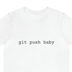 May include: White t-shirt with the text "git push baby" in a simple, black font. The shirt is a basic crew neck style, suitable for casual wear. The text is centered on the front of the shirt.