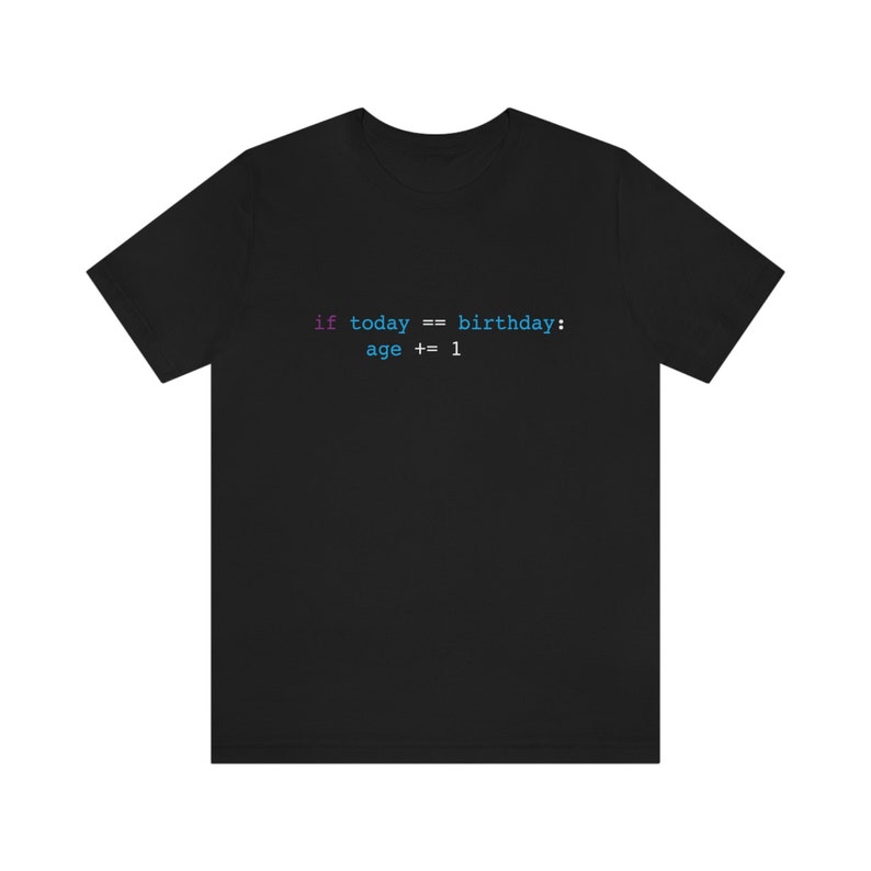 May include: Black t-shirt with the text "if today == birthday: age += 1" in a programming code style. The text is in shades of blue and purple. The shirt is made of a soft material.