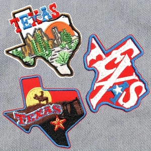 May include: Three embroidered iron-on patches shaped like the state of Texas. The patches feature different designs, including a sunset, a cowboy boot, and a star. The patches are all red, white, and blue.