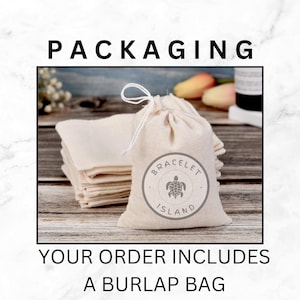 May include: A stack of folded beige fabric and a drawstring burlap bag with the text "BRACELET ISLAND" and a turtle graphic. The text "PACKAGING" is at the top, and "YOUR ORDER INCLUDES A BURLAP BAG" is at the bottom.