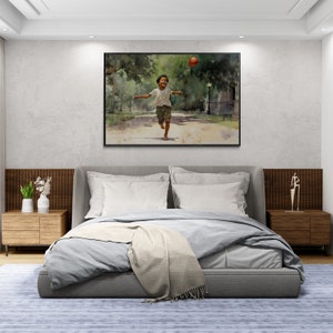 May include: A bedroom interior with a gray upholstered bed with white bedding and a throw blanket. A framed watercolor painting of a young boy running with a red ball in a park hangs on the wall above the bed. Two wooden nightstands with lamps are on either side of the bed.
