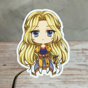 May include: A sticker featuring a chibi-style illustration of a female character with long, flowing blonde hair and large blue eyes. She wears a blue and yellow outfit and holds a sword. The sticker has a white border.