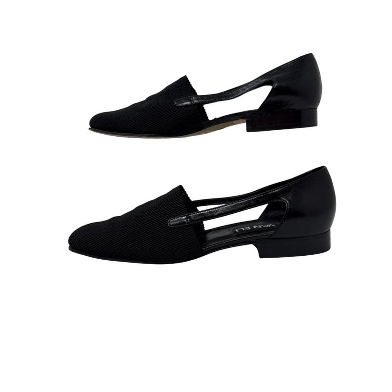 May include: Black leather and fabric slip-on shoes with a cut-out design. The shoes have a low heel and a pointed toe.