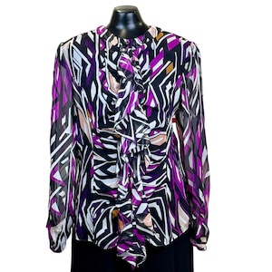 May include: A long-sleeved blouse with a ruffled neckline and a geometric print in shades of black, white, purple, and brown.