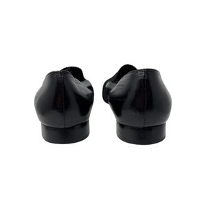 May include: A pair of black leather ballet flats with a pointed toe.