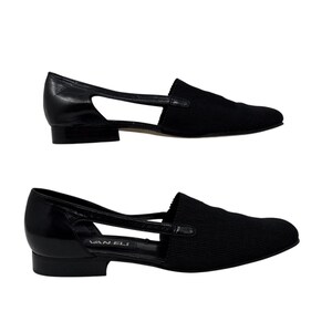 May include: A pair of black leather and fabric slip-on shoes with a cut-out detail and the brand name "Van Eli" on the sole.