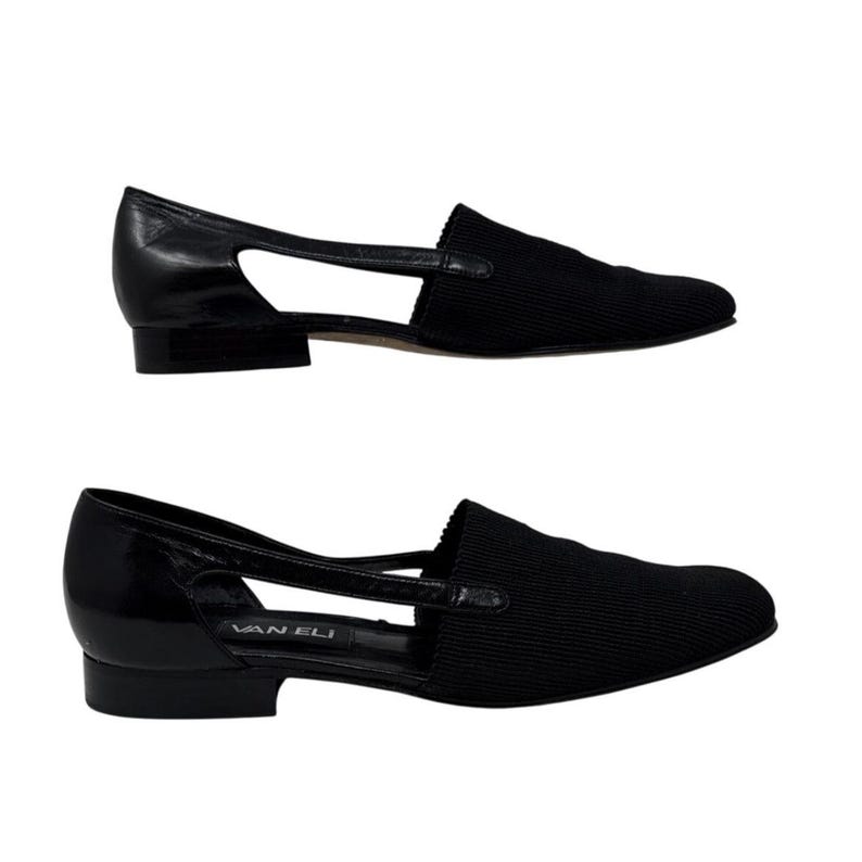 May include: A pair of black leather and fabric slip-on shoes with a cut-out detail and the brand name "Van Eli" on the sole.