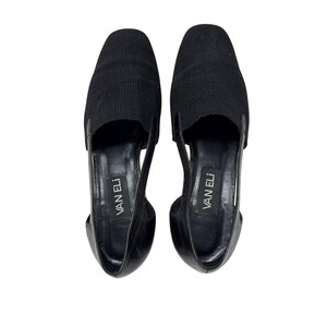 May include: A pair of black leather flats with a cut-out design and the brand name "VAN ELI" printed on the insole.
