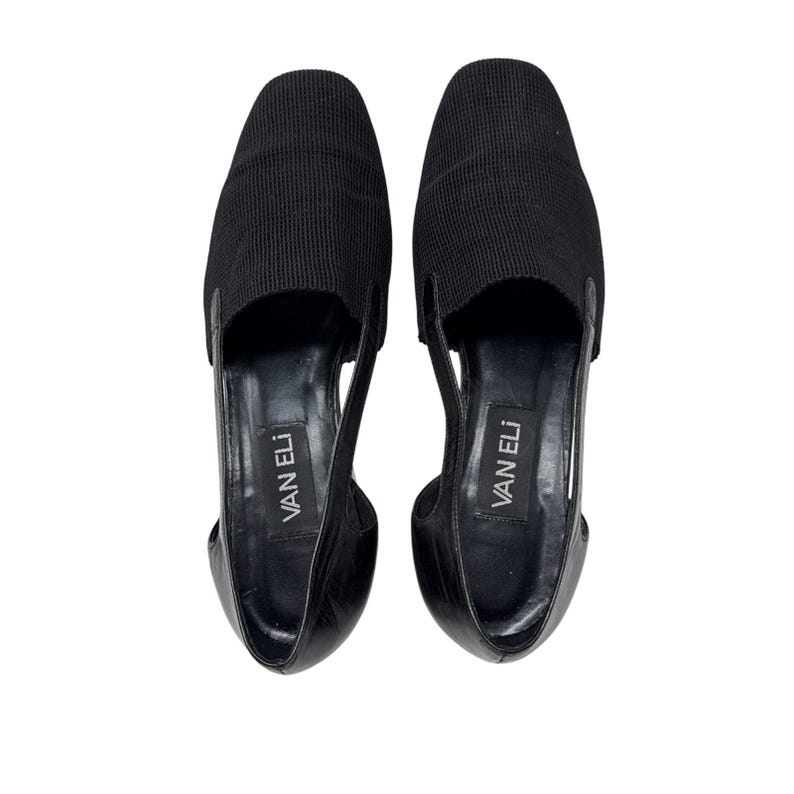 May include: A pair of black leather flats with a cut-out design and the brand name "VAN ELI" printed on the insole.