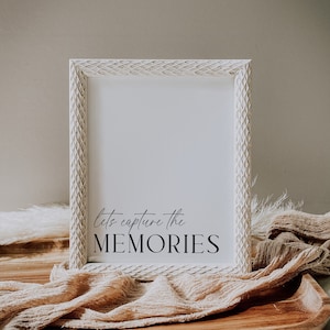 Puede incluir: Marco de fotos blanco con un borde decorativo y el texto "Let's capture the MEMORIES" en escritura negra.