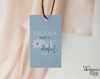 May include: A blue tag with white text that reads "Sienna had a one derful day" with a white daisy with a yellow center.