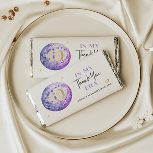 May include: Two white chocolate bars with purple and gold disco ball designs. The text on the chocolate bars reads "In My Thank You Era" and "Sarah's 10th Birthday Era".