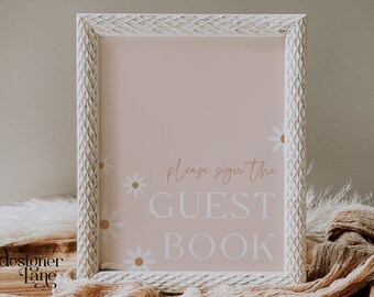 May include: A white frame with a pink background and white daisies. The text "Please sign the GUEST BOOK" is written in brown cursive lettering.