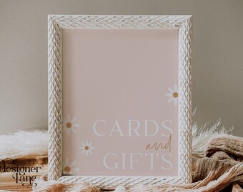 May include: White framed sign with a pink background and white text that says "CARDS and GIFTS". The sign has a decorative white frame and small white daisies with yellow centers.
