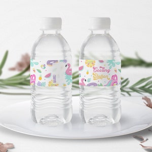 Könnte beinhalten: Zwei durchsichtige Plastikwasserflaschen mit bunten Etiketten. Die Etiketten zeigen ein tropisches Thema mit Flamingos, Ananas, Wassermelonen und dem Text "Cooling Station".