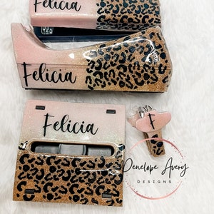 May include: A desk set featuring a stapler, tape dispenser, and note holder, all finished in a pink and gold glitter gradient with a black leopard print pattern. Each item is personalized with the name Felicia in black script lettering.