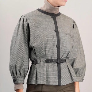 May include: A black and white gingham patterned blouse with a black trim and a black belt. The blouse has a cinched waist and long sleeves with puffed shoulders.