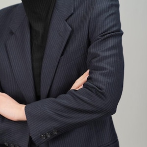May include: A navy blue pinstripe blazer with a single button closure. The blazer has a notched lapel and long sleeves with button cuffs.