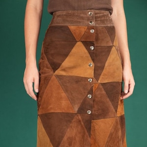 Könnte beinhalten: Ein brauner Wildledrock mit einem Patchwork-Design aus Dreiecken. Der Rock hat einen Knopfverschluss vorne.