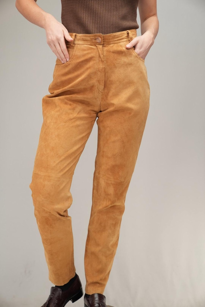 May include: A pair of high-waisted, light brown suede trousers.