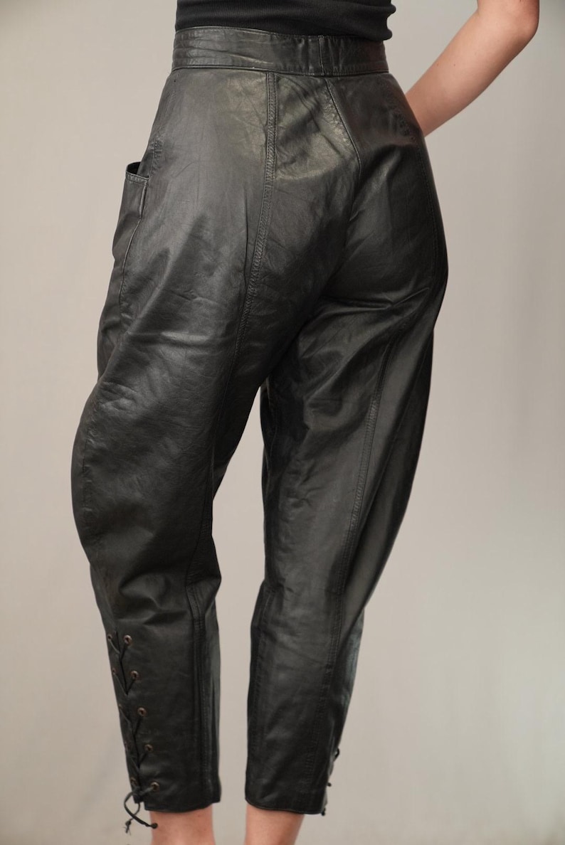 May include: Black leather pants with a high waist and lace-up detailing at the ankles.