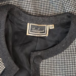 May include: A black and white houndstooth jacket with a black collar and a label that reads "Luis Lagnol" and "Made in Italy". The label also has a size tag that reads "46".