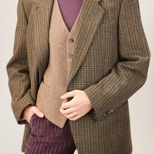 May include: A brown and green plaid blazer with a matching brown vest and a purple turtleneck. The blazer has a classic cut with a two-button closure and a pocket on the chest. The vest has a three-button closure. The pants are purple corduroy.