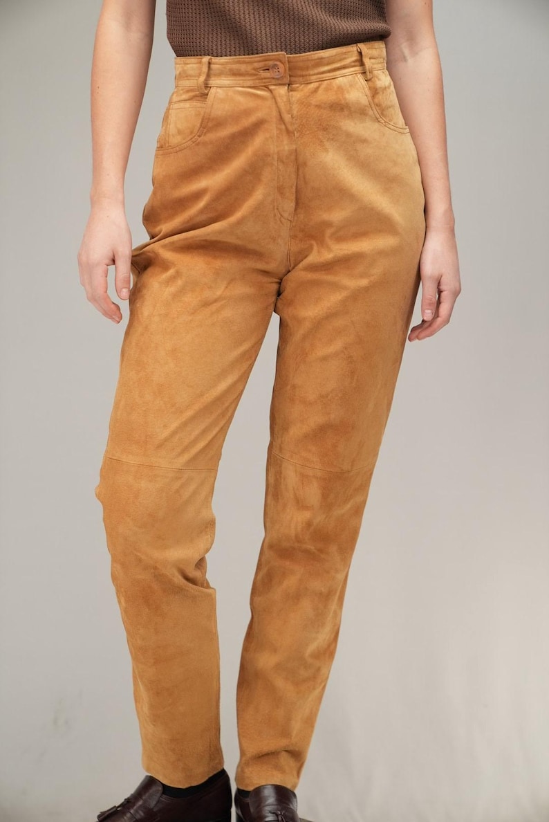 May include: A pair of high-waisted brown suede trousers.
