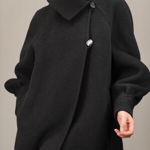 May include: A black wool coat with a large collar and a single button closure. The coat has a relaxed fit and long sleeves.