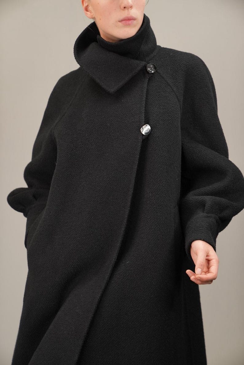 May include: A black wool coat with a large collar and a single button closure. The coat has a relaxed fit and long sleeves.