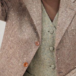 May include: A brown tweed jacket with a matching brown tweed waistcoat. The jacket has a button fastening and the waistcoat has a button fastening and a pocket on the left side.