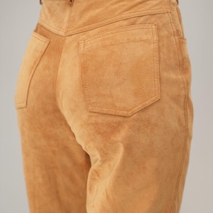 May include: A pair of brown suede pants with a back pocket and a high waist.