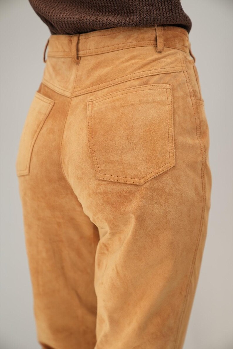 May include: A pair of brown suede pants with a back pocket and a high waist.
