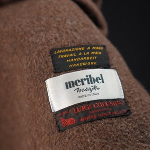 K&ouml;nnte beinhalten: Nahaufnahme eines braunen Wollstoffes mit einem wei&szlig;en Etikett, auf dem "meribel Marretto Made in Italy" steht, und einem braunen Etikett, auf dem "L.ANERIE LUIGI COLOMBO BORGOSESA SUPREME ALPACA MERINO" steht. Das Etikett enth&auml;lt auch den Text "LAVORAZIONE A MANO TRAVAIL A LA MAIN HANDARBEIT HANDWORK".