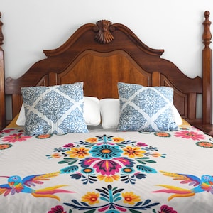 May include: A white bed with a floral and bird patterned duvet cover. The bed has a wooden headboard with a carved design. Two blue and white patterned pillows are on the bed.