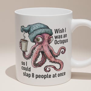 May include: White ceramic mug with a cartoon octopus design. The octopus, in a blue beanie, holds a coffee cup. The octopus is pink with large eyes and tentacles. Text on the mug reads, "Wish I was an Octopus so I could slap 8 people at once."